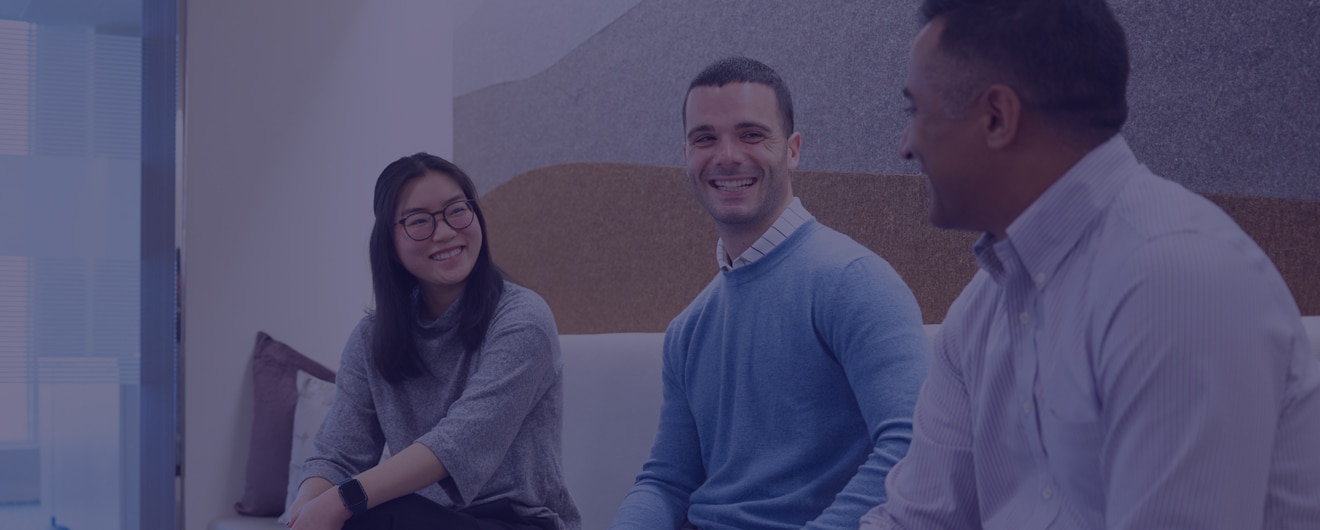 Three colleagues sitting and chatting, smiling to camera