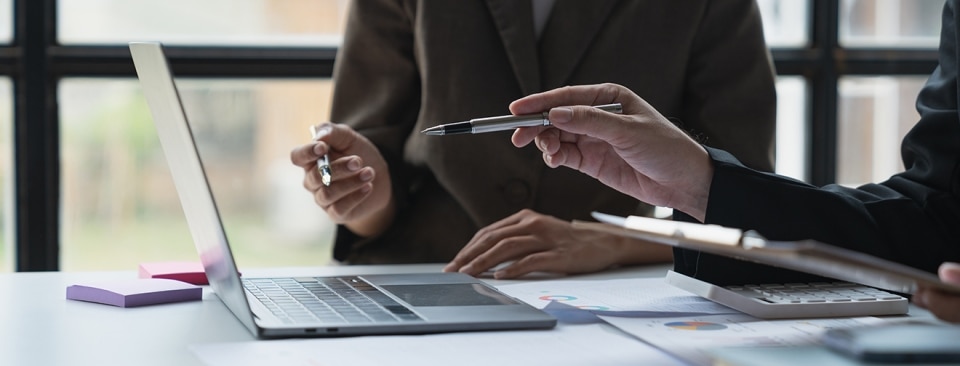 Two people's hands pointing to a laptop screen